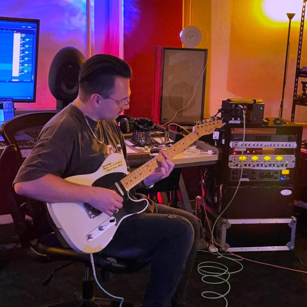 Luka playing electric guitar in a studio.